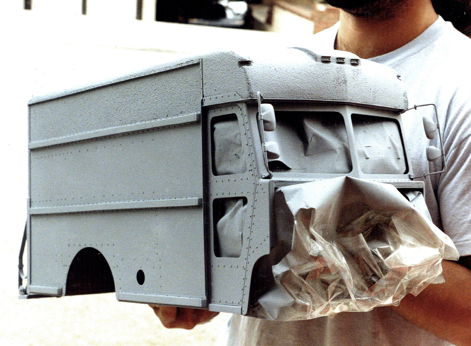 A scale UPS delivery truck miniature in primer in the Lowtech shop, with Adam's hand visible for scale